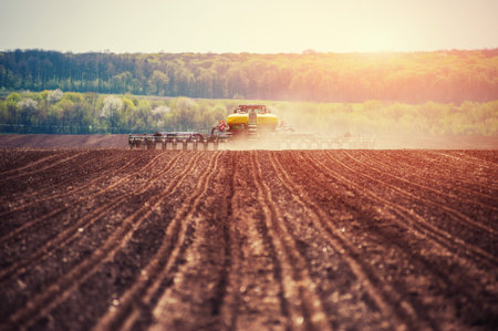 Tractor plowing farm field in preparation for spring planting
