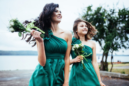 Happy young women at a wedding with bouquets of flowersの写真素材