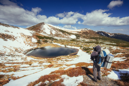 Mountain Lake. Sky reflected in the water. A tourist looks at the landscape. Spring landscape. Carpathian Mountains, Ukraineの写真素材