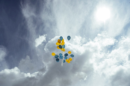 bouquet of blue and yellow balloons in the sky.の写真素材