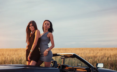 Two women in a black car on the roadside roads.の写真素材