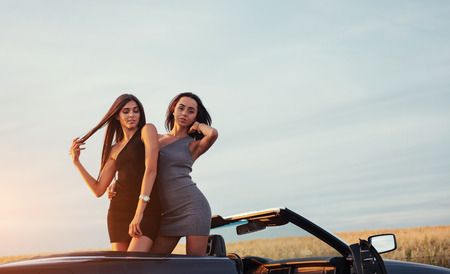 Two women in a black car on the roadside roads.の写真素材