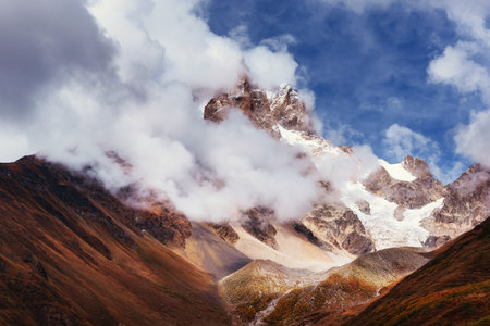 Autumn landscape and snow mountains in beautiful cumulus clouds.