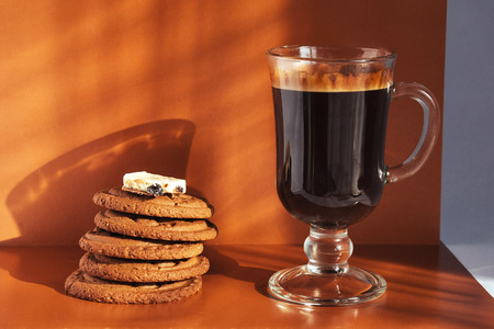Glass cup of hot coffee with cookies and chocolateの写真素材