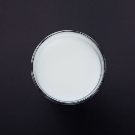 Transparent glass of milk on a black background.の写真素材
