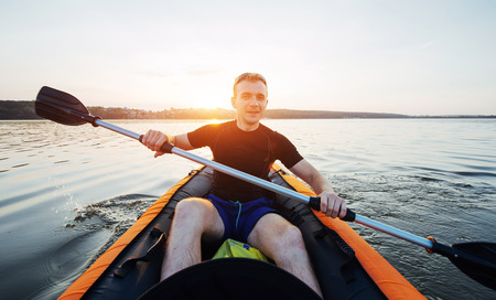 man floating on lake in a kayak at fantastic sunset.の写真素材