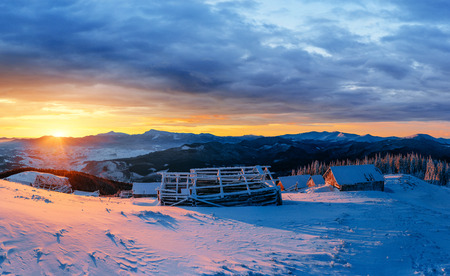 Fantastic sunset over snow-capped mountains and wooden chaletsの写真素材