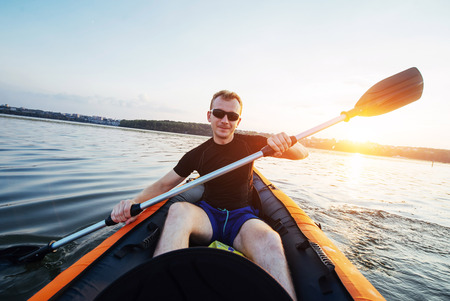 man floating on lake in a kayak at fantastic sunset.の写真素材