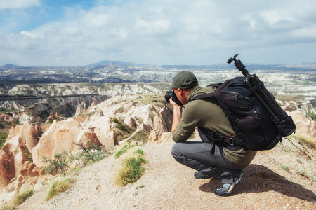 Photographer sandstone cliff and observing the natural landscape, Cappadocia, Turkeyの写真素材