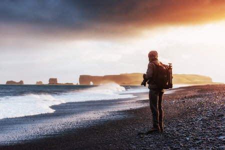 Famous Reynisdrangar rock formations at black Reynisfjara Beach. Photographer making successful...