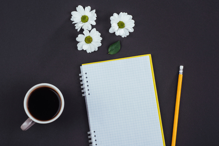 On a black background notebook pencil, fragrant coffee and white flowersの写真素材