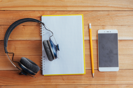 Headphones and notebook and pencil on a brown wooden background.の写真素材