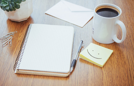 notepad and pen beside a cup of coffee on a wooden table outdoors at a cafeの写真素材