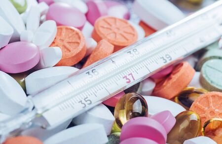Thermometer and different colored types of pills. Medical health or drugs concept.の写真素材