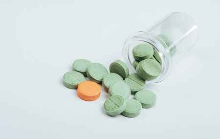 Medical green and one orange pill for the treatment and health care on a white background.