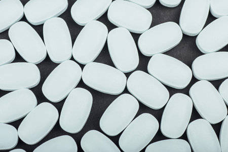 Medical white tablets or supplements for the treatment and health care on a black background.