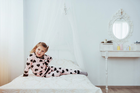 Child in soft warm pajama playing in bed.の写真素材