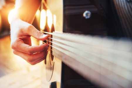 Guitarist plays guitar on wooden background, close up.の写真素材