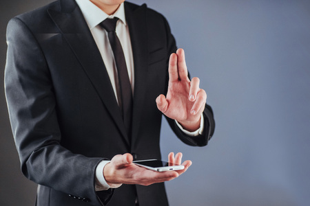 Businessman with a phone in his hand. A student in a suit on a dark backgroundの写真素材