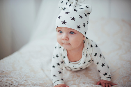 Newborn baby dressed in a white suit and black stars is a white soft bed in the studio.の写真素材