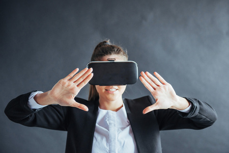 Happy woman on background in the studio gets the experience of using VR-glasses virtual reality headsetの写真素材