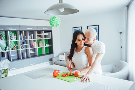 Beautiful young couple grinds vegetables together in the kitchen.の写真素材