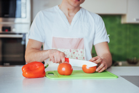 man cuts vegetables together in the kitchenの写真素材