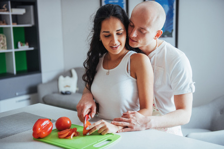 Beautiful young couple grinds vegetables together in the kitchen.の写真素材