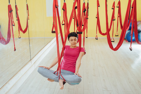 Young beautiful woman practicing yoga Fly with a hammock in studio.の写真素材