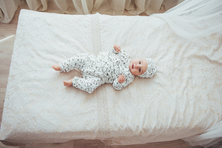 Newborn baby dressed in a suit on a soft bed in the studio.の写真素材