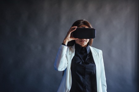 Happy woman on a black background in the studio gets the experience of using VR-glasses virtual reality headset.の写真素材