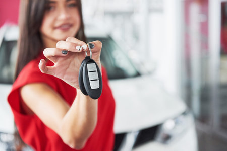 Smiling car salesman handing over your new car keys, dealership and sales concept. Happy girl the...