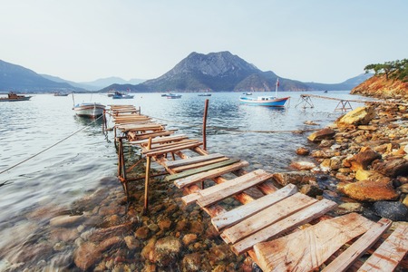 Boats near the broken pier, putting in a tranquil calm blue sea water.の写真素材