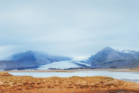 Gentle slopes of snow-capped mountains and glaciers. Wonderful Iceland in the springの写真素材