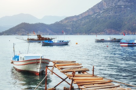 Boats near the broken pier, putting in a tranquil calm blue sea water.の写真素材