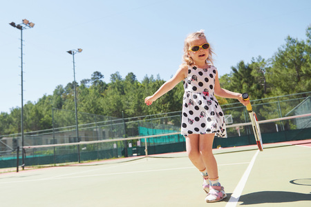 Happy little girl playing tennisの写真素材