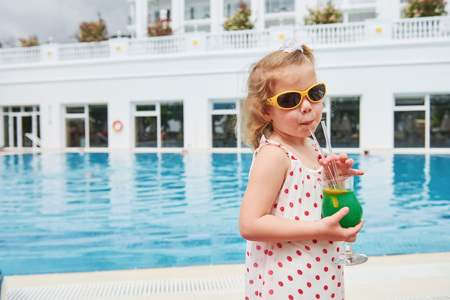 Cute little blonde at the pool and holding a childs cocktailの写真素材