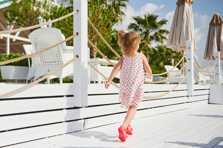 Happy baby girl in a dress on the beach by the sea in summer.の写真素材