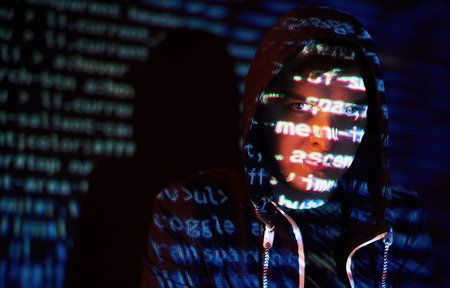 Cyber attack with unrecognizable hooded hacker using virtual reality, digital glitch effectの写真素材