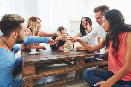 Group of creative friends sitting at wooden table. People having fun while playing board gameの写真素材
