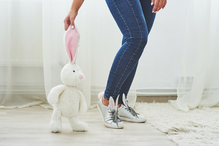 Happy easter. Beautiful sexy young woman wearing bunny ears on shoes and holding cute bunny toyの写真素材