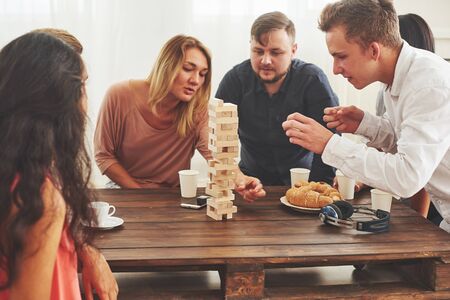 Group of creative friends sitting at wooden table. People having fun while playing board gameの写真素材