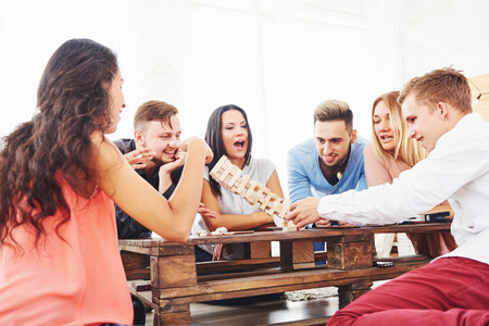 Group of creative friends sitting at wooden table. People having fun while playing board gameの写真素材