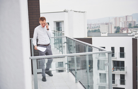 Smiling young architect or engineering builder in hard hat with tablet over group of builders at construction site, architect watching some a construction, business, building, industry, people conceptの写真素材