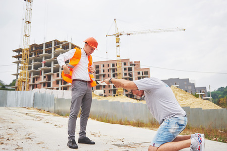 business, building, teamwork and people concept - group of smiling builders in hardhats at construction siteの写真素材