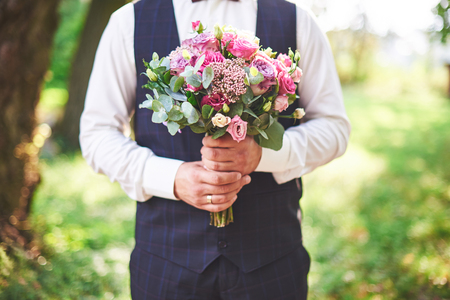 Stylish groom holding a tender pink wedding bouquet.の写真素材