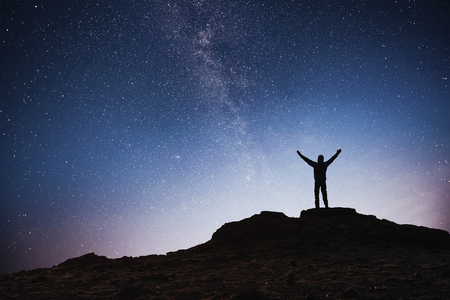Silhouette young man background of the Milky Way galaxy on a bright star dark sky tone.の写真素材