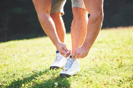 Tying sports shoe. A young sportsman getting ready for athletic and fitness training outdoors....