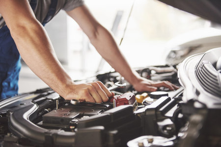 Auto mechanic working in garage. Repair service.