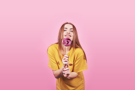 Girl cute funny portrait holding lollipop smiling on pink background. Beautiful multicultural Caucasian girl smiling happy.の写真素材